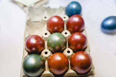 Multi colored Easter eggs in tray on table at home - MRRF00880