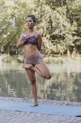 Athlete doing yoga while standing on one leg at park - MFF07109