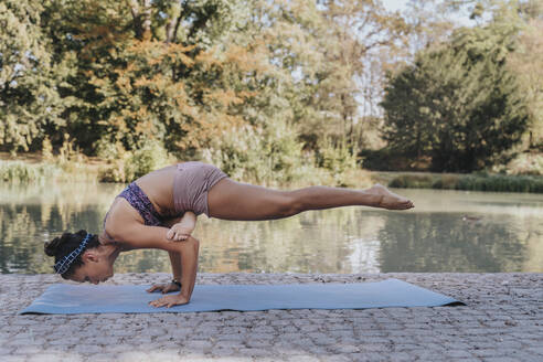 Älterer Sportler balanciert beim Üben von Handstand-Yoga auf einer Matte im Park - MFF07110