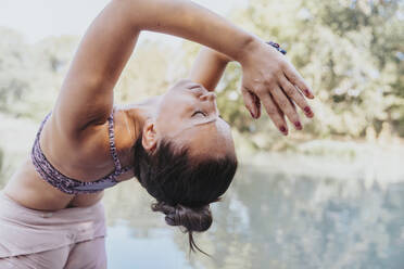 Mature athlete with hands clasped practicing yoga while sitting at park - MFF07113