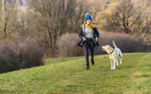 Junge Frau mit Hund läuft in der Natur - STSF02822