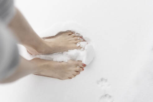 Woman standing barefoot in snow - CHPF00751