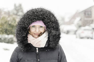 Frau im Anorak mit Kapuze bei Schneefall - CHPF00753