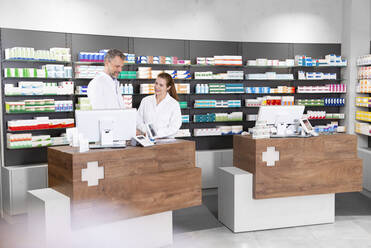 Männliche und weibliche Pharmazeuten an der Apothekenkasse - FKF03995