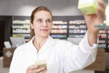 Smiling female pharmacist with medicine in store - FKF04001