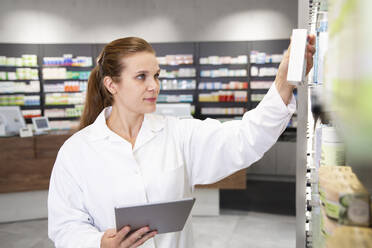 Apothekerin mit digitalem Tablet zur Überprüfung von Medikamenten im Geschäft - FKF04005