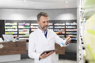 Male pharmacist with digital tablet doing inventory - FKF04006