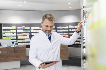 Male pharmacist doing inventory with digital tablet - FKF04007