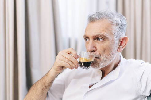Nachdenklicher Mann trinkt Kaffee in einem Hotelzimmer - DGOF01927
