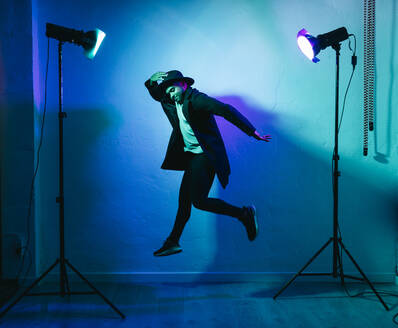 Mann in Freizeitkleidung tanzt vor farbigem Hintergrund - DGOF01975