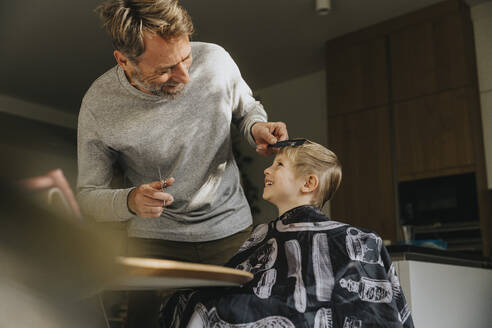 Sohn lacht mit Vater beim Haarschnitt zu Hause - MFF07132