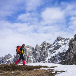 Man hiking on snowcapped mountain against cloudy sky - MCVF00731