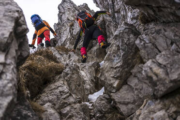 Men with backpack climbing on rocks - MCVF00733