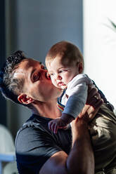 Mann küsst kleinen Jungen, während er zu Hause steht - PGF00434