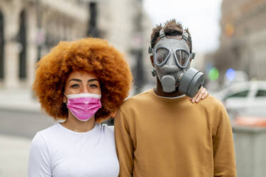 Paar mit Gesichtsschutzmaske, das im Freien steht und starrt - OCMF02068