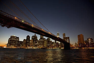 USA, New York, New York City, Brooklyn Bridge bei Nacht mit der Skyline von Manhattan im Hintergrund - AJOF01024