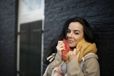 Beautiful woman in warm clothing against black brick wall during winter - AXHF00179