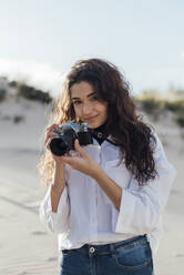 Schöne junge Frau mit Vintage-Kamera steht gegen den Himmel - JRVF00271