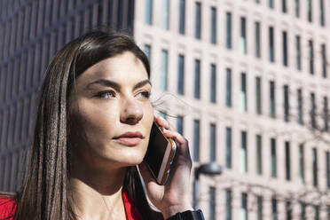 Schöne Geschäftsfrau, die mit dem Handy telefoniert und gegen ein Gebäude schaut - PNAF00624