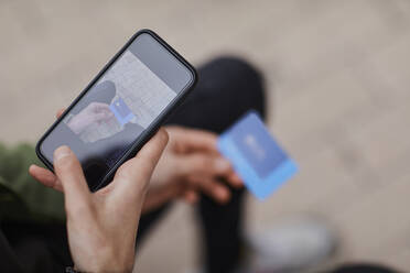 Mann fotografiert seine Kreditkarte mit dem Smartphone - ACPF01120