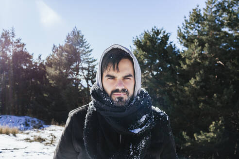 Bärtiger Mann in warmer Kleidung steht auf schneebedecktem Land gegen den Himmel - MGRF00168