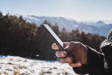 Mann benutzt Mobiltelefon auf verschneitem Land im Winter - MGRF00171