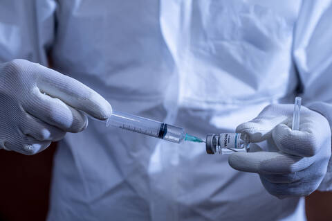 Mature man filling syringe through vial stock photo
