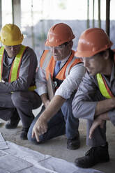 Ein männlicher Architekt erklärt Bauarbeitern auf der Baustelle die Pläne - AJOF01028