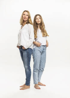 Mutter und Tochter mit Händen in den Taschen stehen vor weißem Hintergrund - DHEF00557