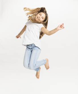 Lächelndes Mädchen springt vor weißem Hintergrund - DHEF00563