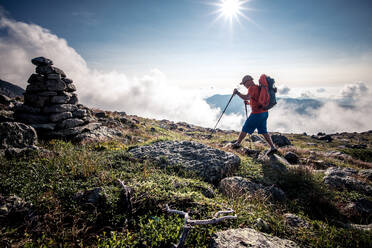 Mann wandert mit Rucksack und Wanderstöcken durch die Berge - CAVF93188