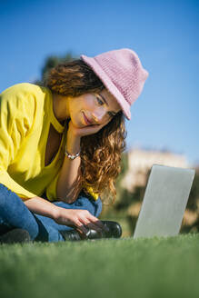 Junge Frau benutzt Laptop im Gras - CAVF93225