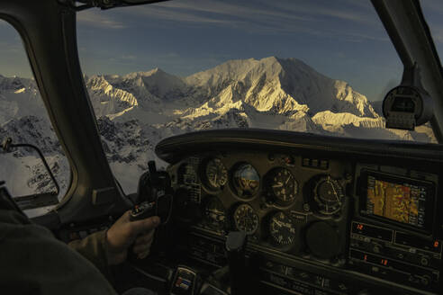 Mann fliegt ein Kleinflugzeug bei Sonnenuntergang mit Alpenglühen auf dem Foraker - CAVF93237