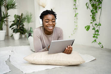 Junge Geschäftsfrau lachend bei der Verwendung eines digitalen Tablets im Wohnzimmer - RCPF00678