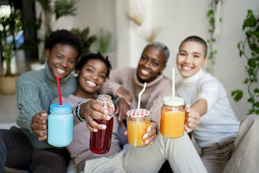 Multiethnische Freundinnen mit Saft zu Hause - RCPF00694