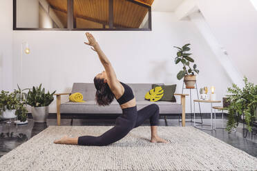 Frau übt Yoga-Pose gegen Sofa im Wohnzimmer zu Hause - MFF07139