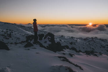 Junge Frau mit roter Jacke beobachtet die letzten Sonnenstrahlen, Tongariro National Park, Neuseeland - CAVF93255