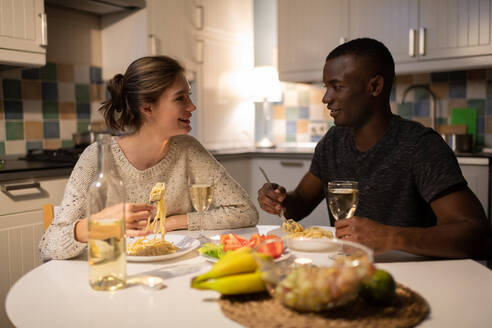 Multiethnisches Paar, das abends zu Hause Nudeln isst - CAVF93317
