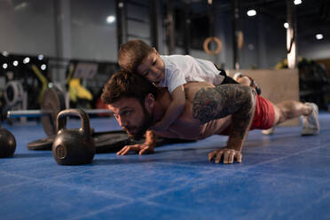 Father and son doing push ups together in gym - CAVF93322