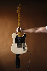 Männlicher Musiker hält seine Gitarre an die Wand - JCMF01891