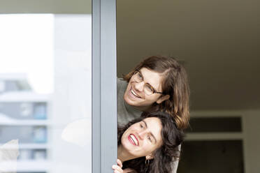 Cheerful couple peeking through glass window - SGF02757