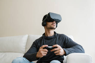 Young man playing video game through virtual reality simulator - EGAF01751