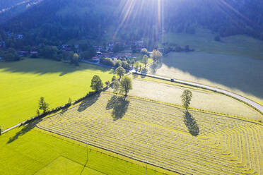 Deutschland, Bayern, Bayrischzell, Drohnenansicht eines grünen Bergfeldes mit Dorf im Hintergrund - SIEF10101