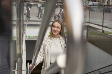 Smiling beautiful woman moving up from subway station through staircase - VEGF03912