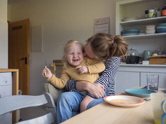 Cheerful mother embracing daughter in kitchen at home - LAF02681
