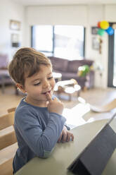 Junge benutzt digitales Tablet beim Online-Unterricht zu Hause - IFRF00404
