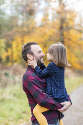 Lächelnder Vater sieht seine Tochter an, während er im Wald steht - WPEF04103