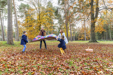 Familie mit Decke im Herbst im Wald stehend - WPEF04110