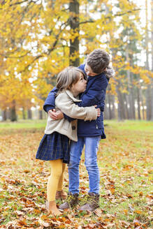 Geschwister, die sich umarmen, während sie im Wald stehen - WPEF04134