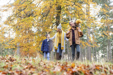 Vater trägt Tochter auf der Schulter bei einem Spaziergang mit der Familie im Wald - WPEF04157